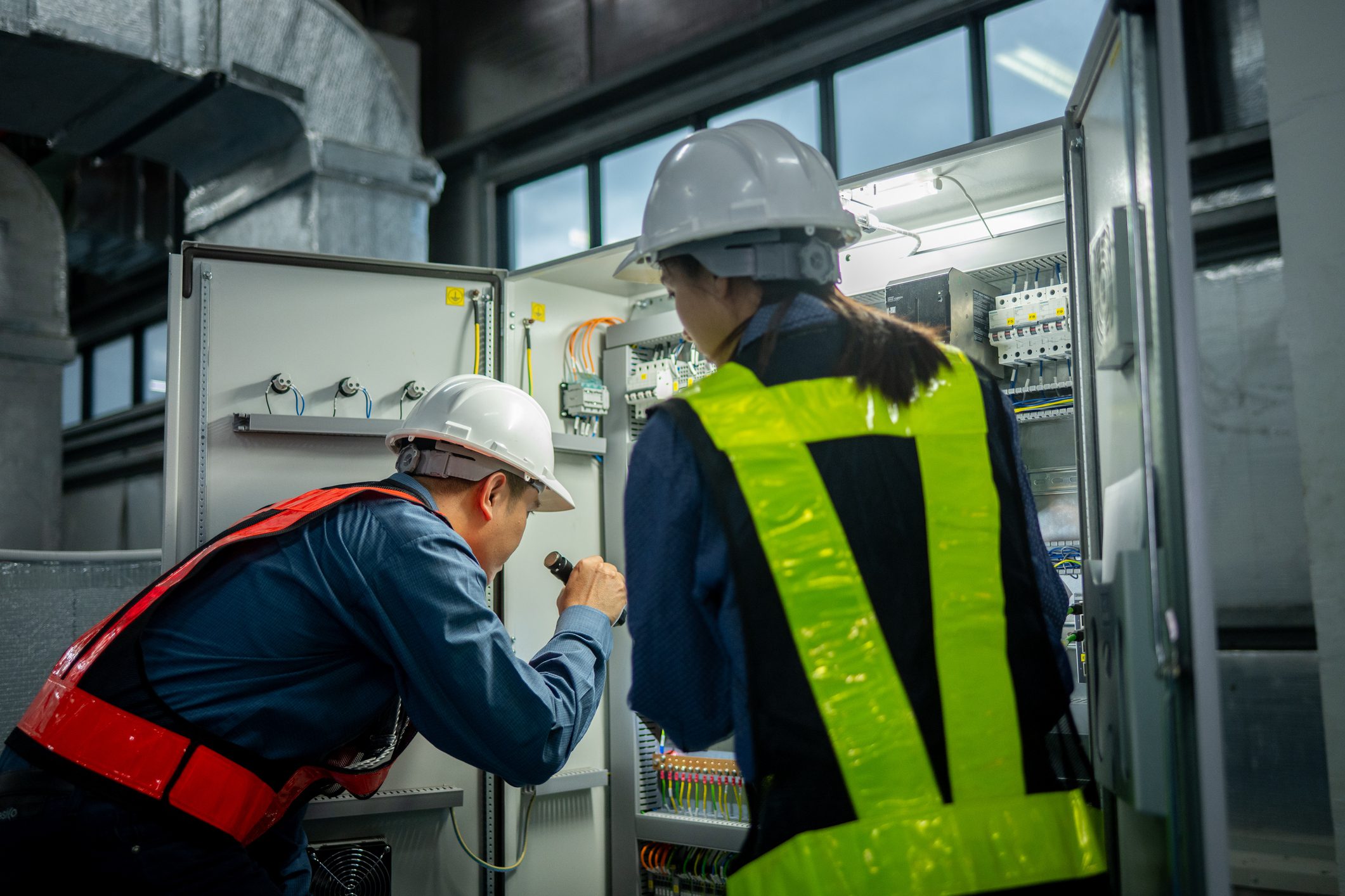 Workers examining control cabinet